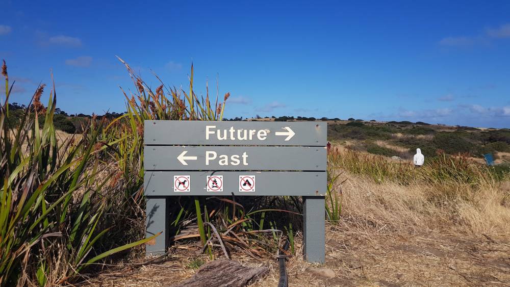 Image of a sign in the middle of the desert with the words "Future" pointing to the right and "Past" pointing to the left