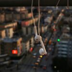 Image focused on white headphones hanging against a twilight sky and a blurred urban background.
