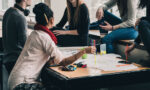 Fotografía de personas alrededor de una mesa en la que se ve una tarjeta con un proyecto.