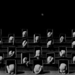 Fotografía en blanco y negro de una grada compuesta por cuerpos desnudos encogidos dentro de cajas con la luna al fondo.