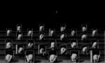 Fotografía en blanco y negro de una grada compuesta por cuerpos desnudos encogidos dentro de cajas con la luna al fondo.