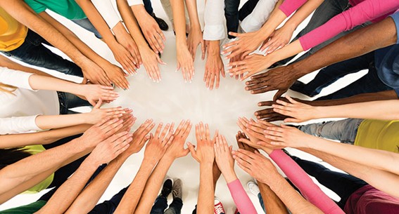 Um grupo de pessoas em roda com as mãos estendidas entre elas dando a ideia de união e trabalho em equipe.