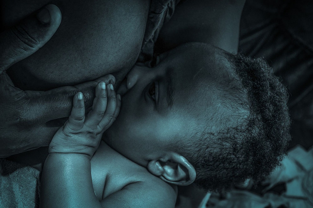 Foto de um bebê sendo amamentado.