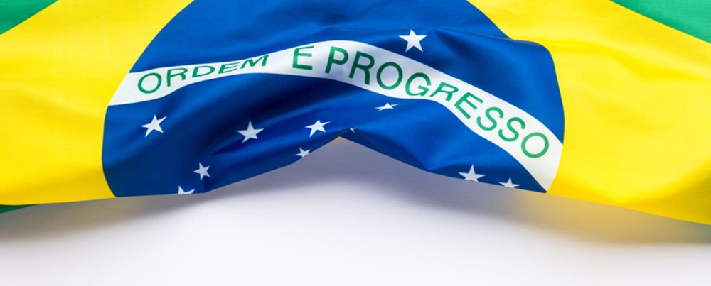 Bandeira do Brasil dobrada sobre um fundo branco.