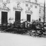 Fotografia em preto e branco do Trâmuei destruído no Quebra-Bondes diante de uma catedral.