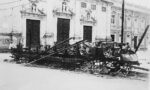 Fotografia em preto e branco do Trâmuei destruído no Quebra-Bondes diante de uma catedral.