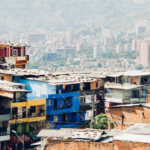 Fotografia de uma cidade, com uma periferia um primeiro plano e de fundo uma parte de cidade com vários prédios